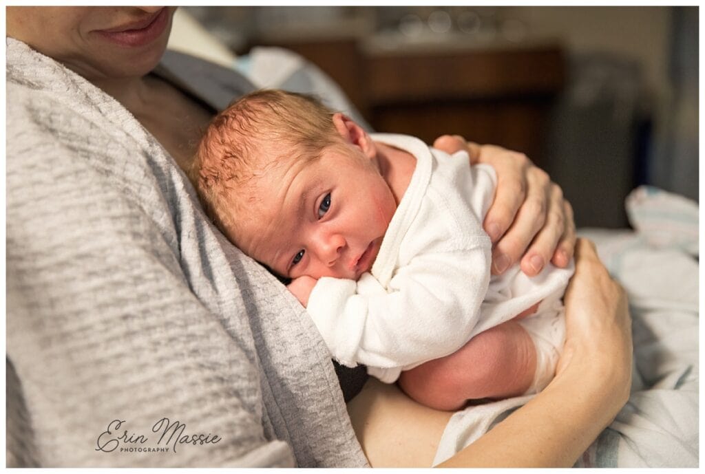 newborn baby curled on mom in the hospital bed during fresh 48 photo session