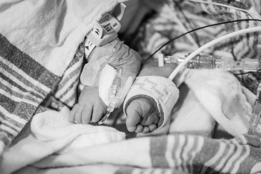 black and white of newborn feet wrapped in hospital blanket and monitors