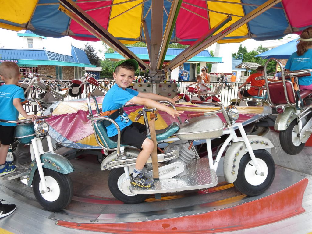 young boy sitting on a spinning motorcycle ride at Michigan's Adventure
