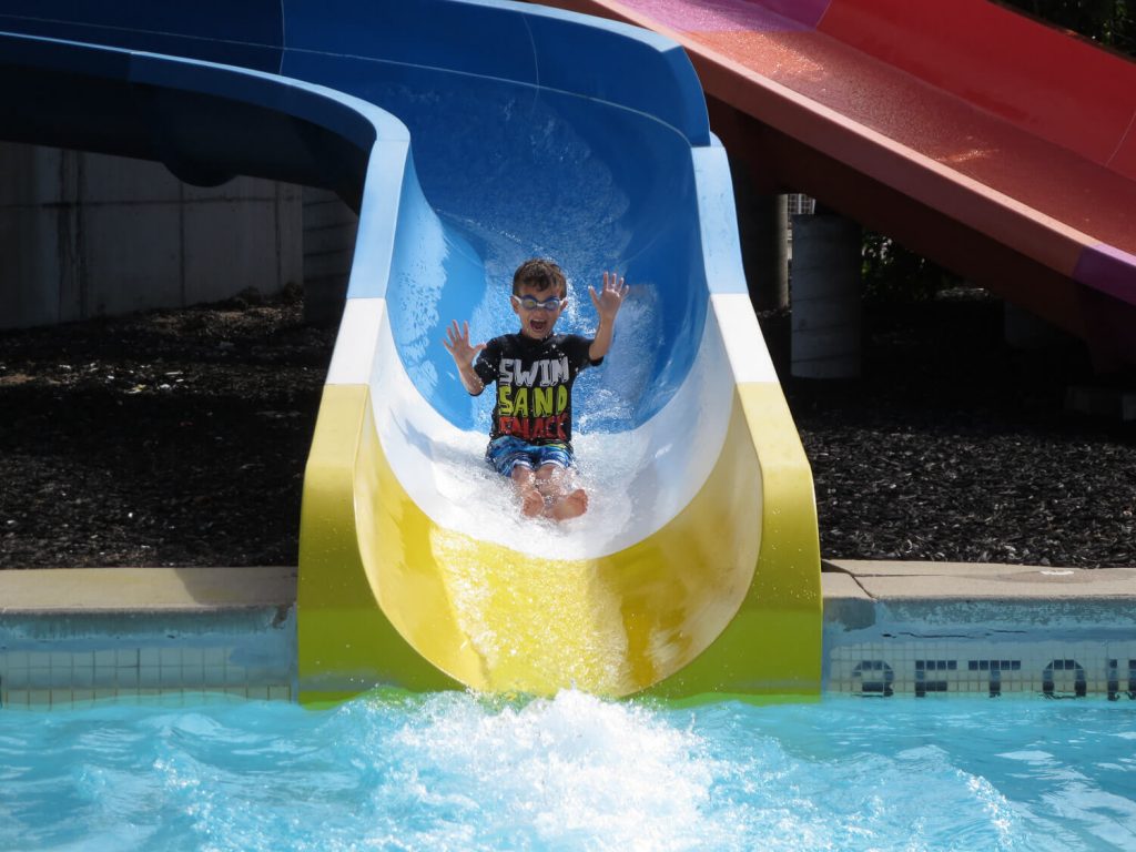 young boy wearing goggles sliding down a water slide at Michigan's Adventure