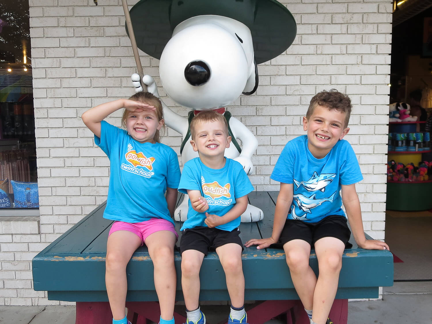 three young siblings sitting on a platform with a Snoopy statue at Michigan's Adventure