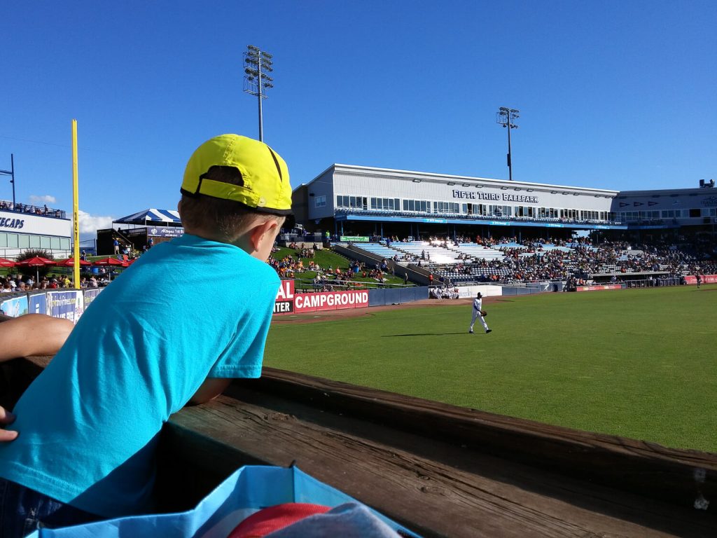young boy leaning over the wall overlooking right field watching the Whitecaps at Fifth Third Ballpark