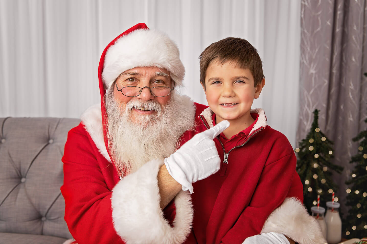 Closeup of Santa pointing to the missing front teeth of a young boy