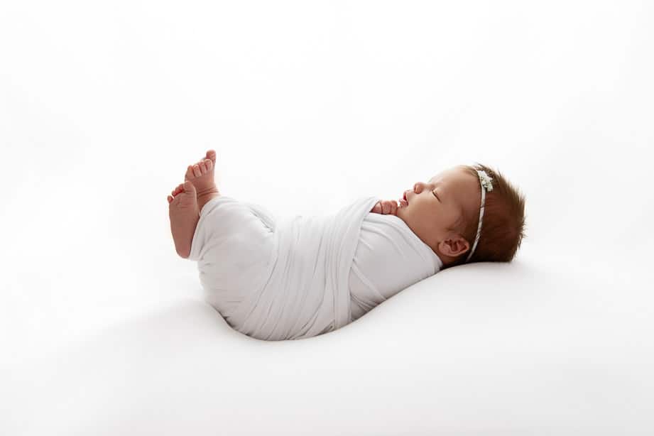 backlit full body profile of baby girl wrapped in white fabric