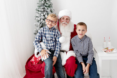Two boys sitting with Santa smiling during their Christmas photo session