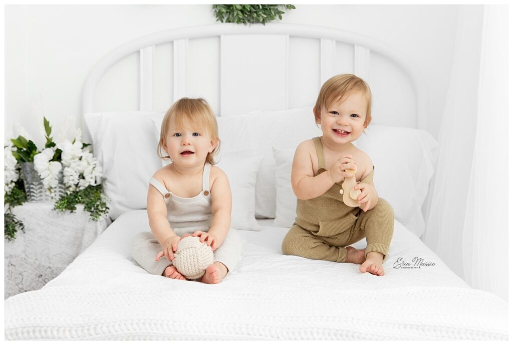 Twin 1 year old boys sitting on a white lifestyle bed