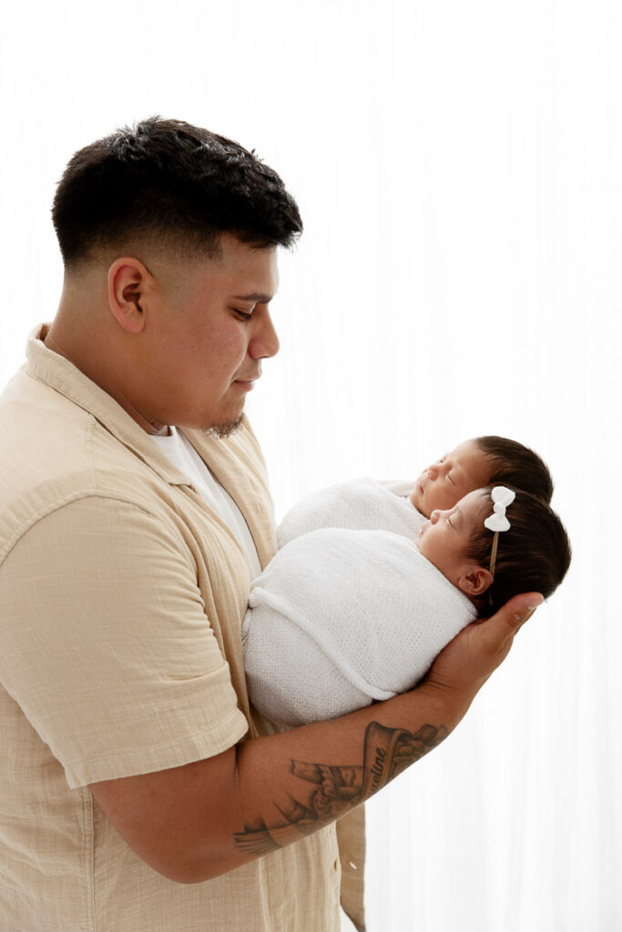 backlit image of dad holding newborn boy girl twins