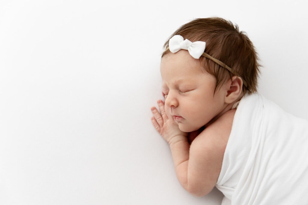 profile view of newborn baby girl sleeping on her stomach with lots of white space to her left