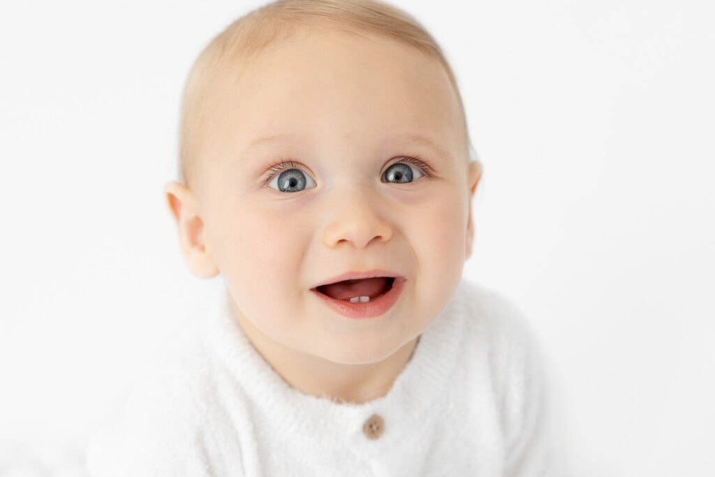 Close up image of baby boy smiling at camera showing first teeth