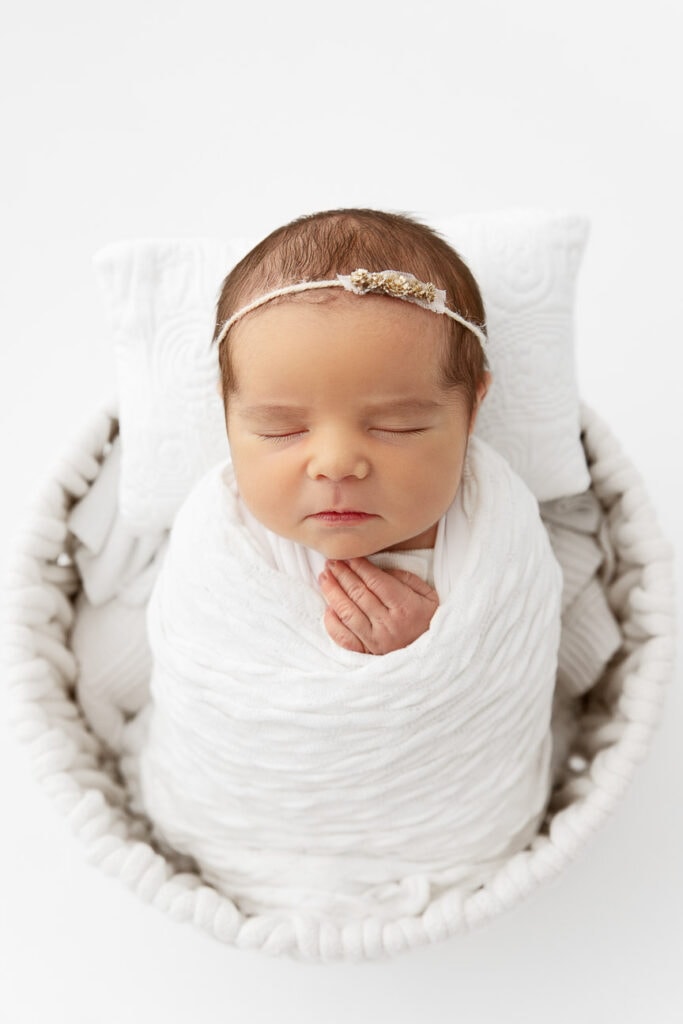 newborn baby girl sleeping wrapped in a bucket prop during a photo session