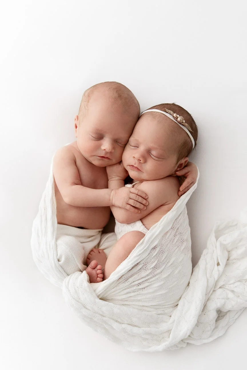 boy and girl twin babies snuggled and sleeping during white studio photo session